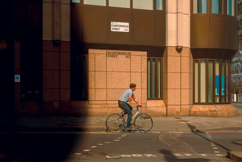 A cyclist pauses at a corner beneath a Charterhouse Street sign in the City of London.