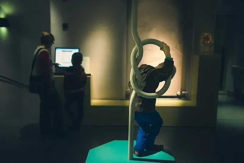 A child plays on a circular exhibit piece while another looks on at a hands-on museum display.