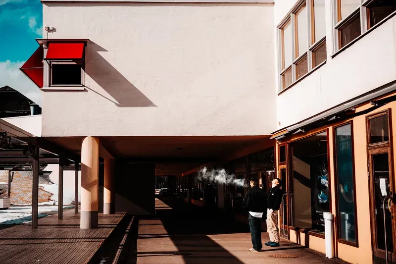 Sharp shadows cut across a bright orange building facade beneath an overhang.